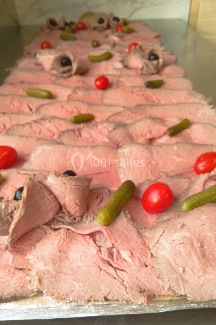 Plateau de tranches de rôti de bœuf garnies de cornichons, tomates cerises et olives noires.
