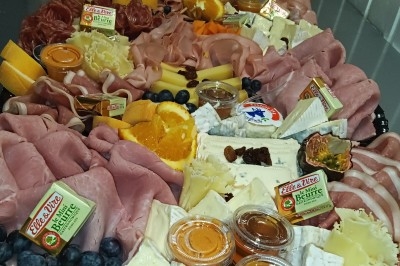 Plateau garni de charcuteries, fromages variés, fruits frais et confitures, présenté pour un buffet ou un apéritif.