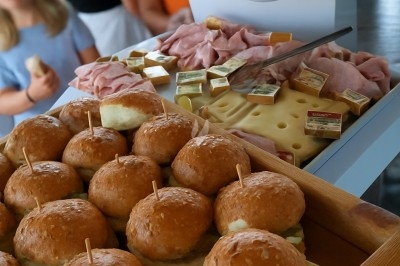 Buffet avec plateau de charcuterie, pommes de terre, salades variées et décoration florale dans une salle de réception.