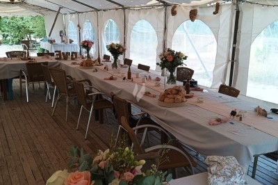 Buffet avec plateau de charcuterie, pommes de terre, salades variées et décoration florale dans une salle de réception.