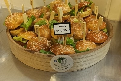 Buffet avec plateau de charcuterie, pommes de terre, salades variées et décoration florale dans une salle de réception.