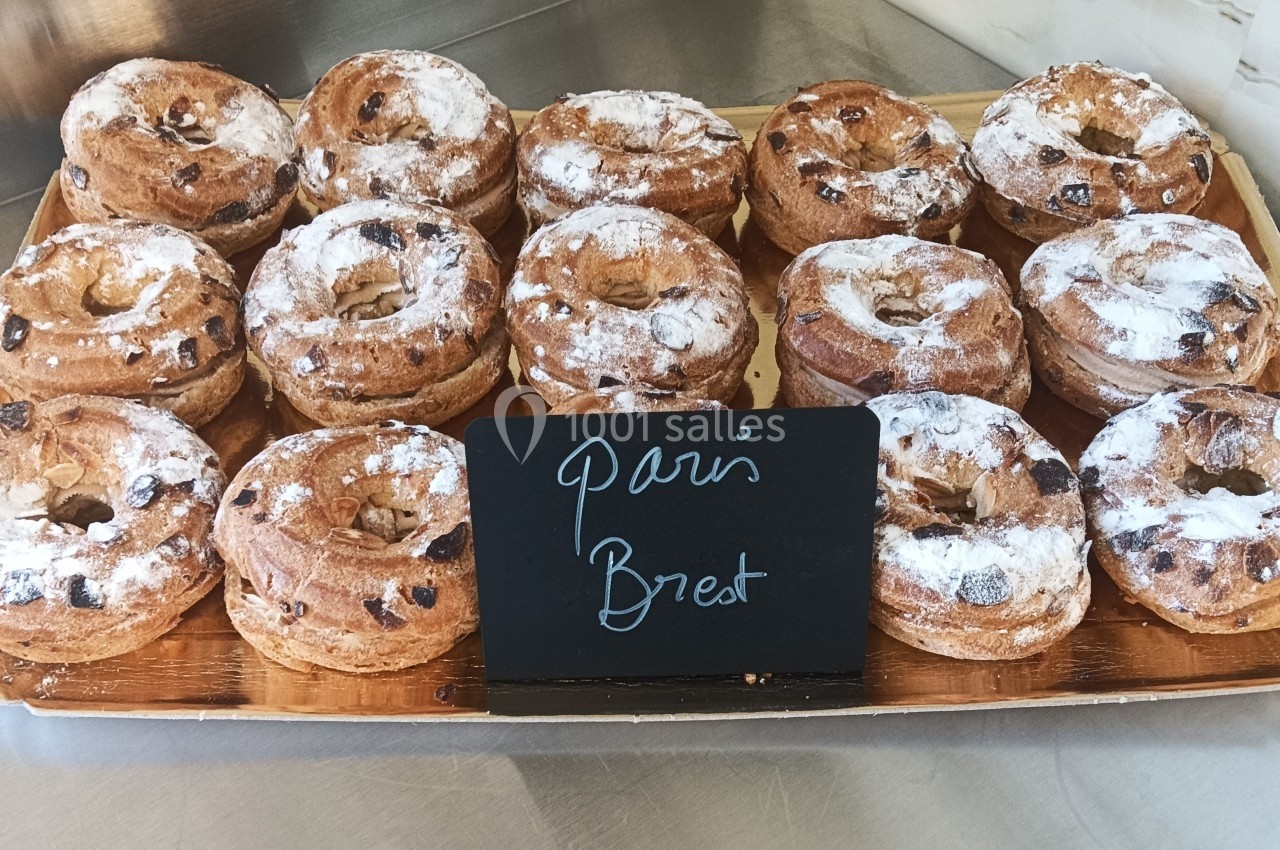 Plateau de Paris-Brest garnis de crème, saupoudrés de sucre glace, exposés sur un comptoir de pâtisserie.