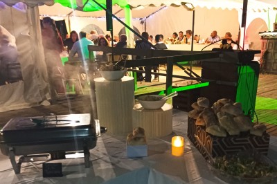 Plan de travail en acier inoxydable sous une fenêtre à double vitrage, dans une pièce aux murs carrelés effet marbre.