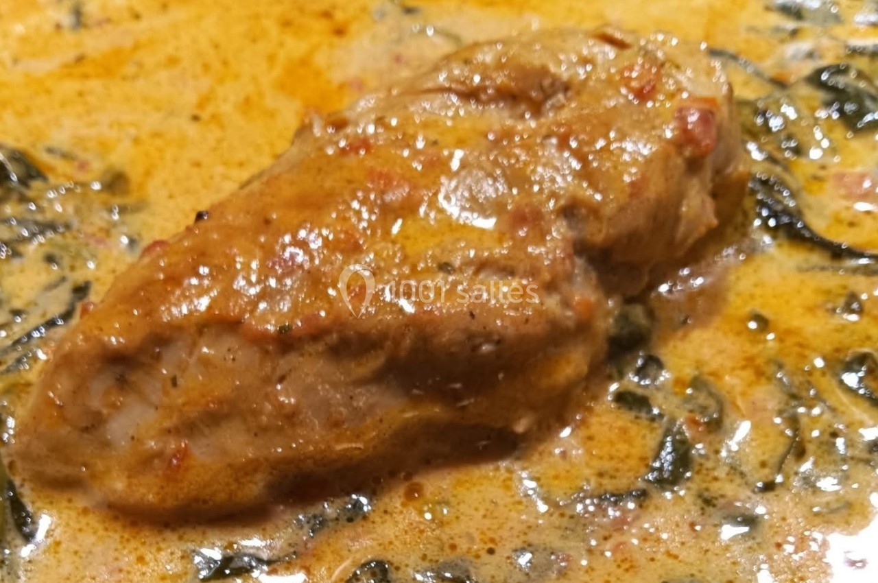 Plat de viande mijotée dans une sauce crémeuse épicée avec des herbes visibles.