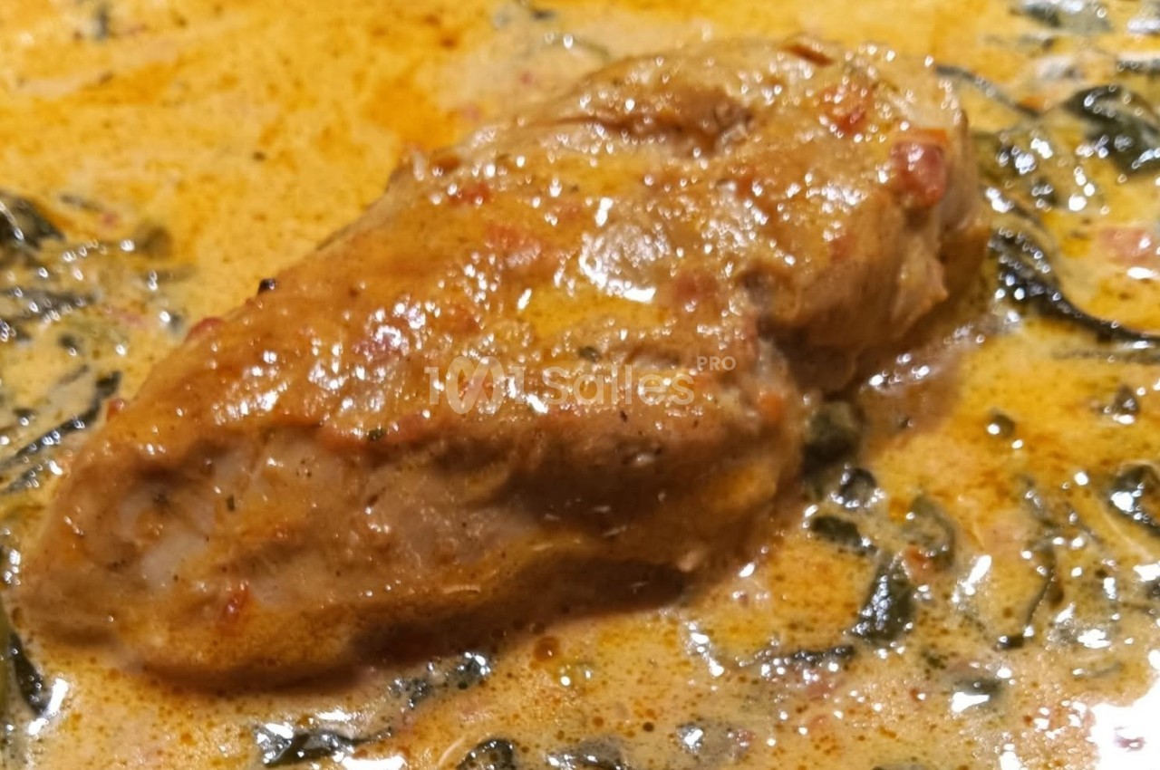 Plat de viande mijotée dans une sauce crémeuse épicée avec des herbes visibles.