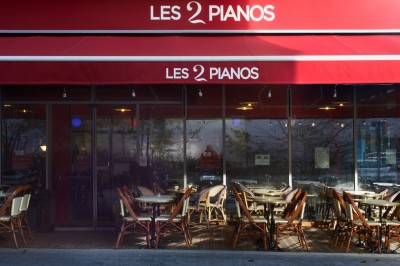 Miniature Location salle Paris 15 (Paris) - Les 2 Pianos #28 Façade d'un restaurant avec terrasse, abritée par un large store rouge, situé en bordure de rue.
