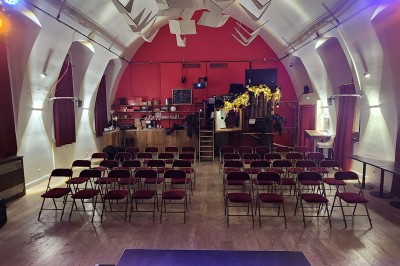 Façade d'un café-restaurant avec terrasse extérieure, tables et chaises sous un auvent rouge marqué ’Les 2 Pianos’.