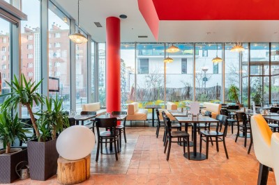 Façade d'un café-restaurant avec terrasse extérieure, tables et chaises sous un auvent rouge marqué ’Les 2 Pianos’.