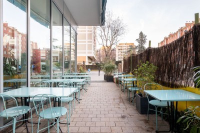 Façade d'un café-restaurant avec terrasse extérieure, tables et chaises sous un auvent rouge marqué ’Les 2 Pianos’.
