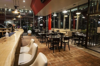 Façade d'un café-restaurant avec terrasse extérieure, tables et chaises sous un auvent rouge marqué ’Les 2 Pianos’.