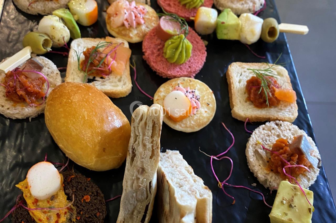 Assortiment de bouchées apéritives variées disposées sur un plateau noir, incluant pains, légumes et garnitures colorées.