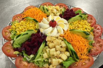 Buffet avec assiettes de salades variées, légumes frais et condiments, disposées sur une table éclairée.