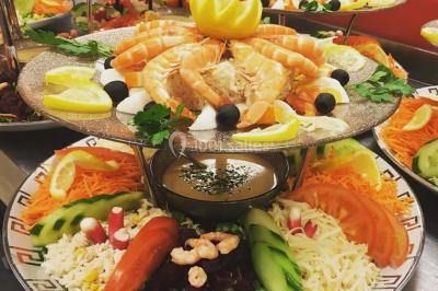 Buffet avec assiettes de salades variées, légumes frais et condiments, disposées sur une table éclairée.