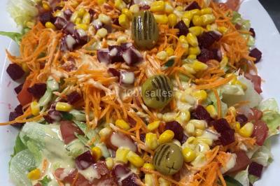 Buffet avec assiettes de salades variées, légumes frais et condiments, disposées sur une table éclairée.