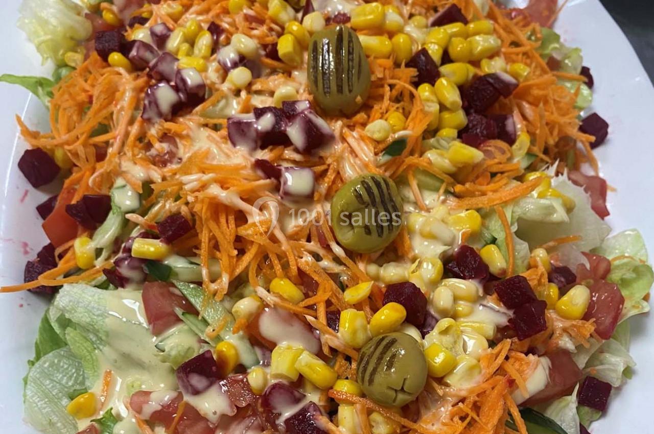 Salade composée avec laitue, carottes râpées, betteraves, maïs, tomates, olives grillées et sauce crémeuse.