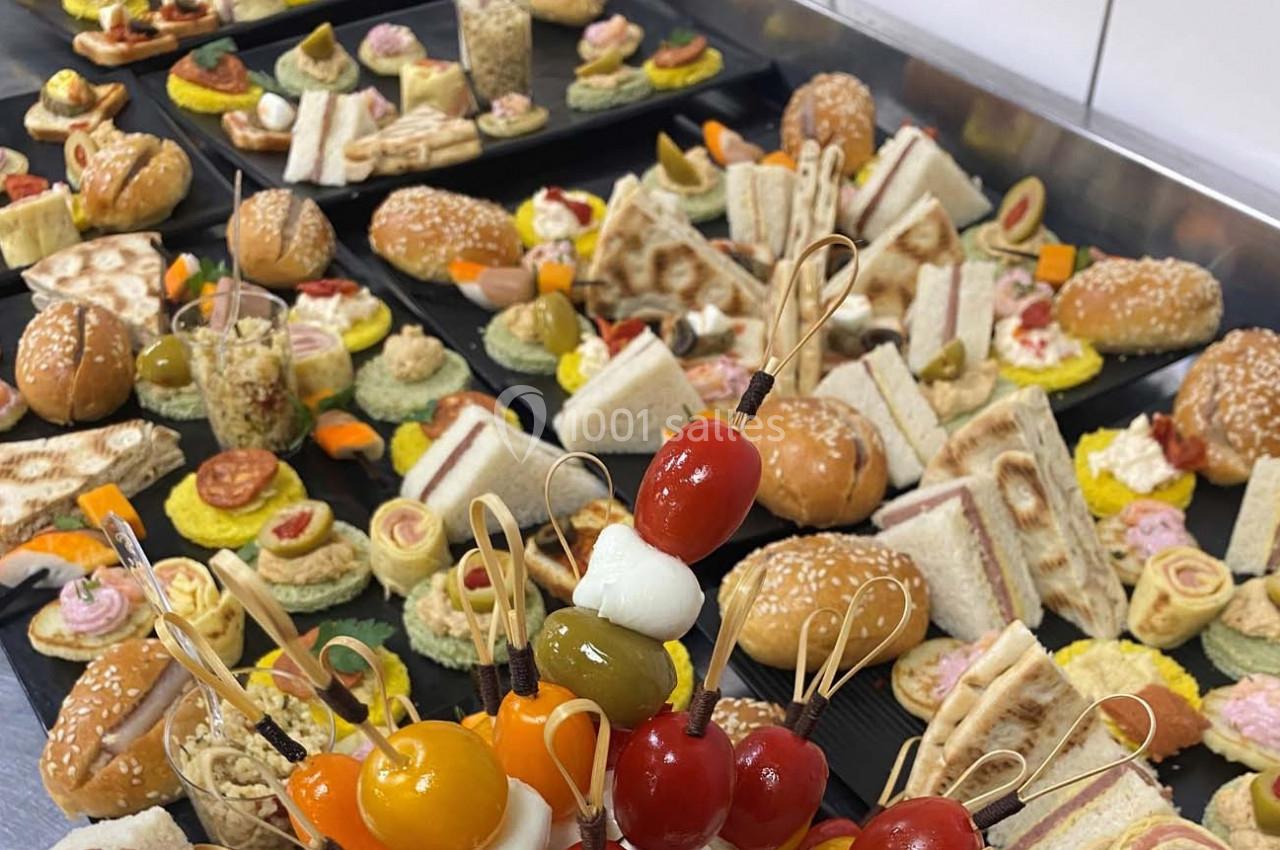 Plateaux variés de bouchées salées, incluant sandwichs, brochettes et amuse-bouches, disposés sur une table.
