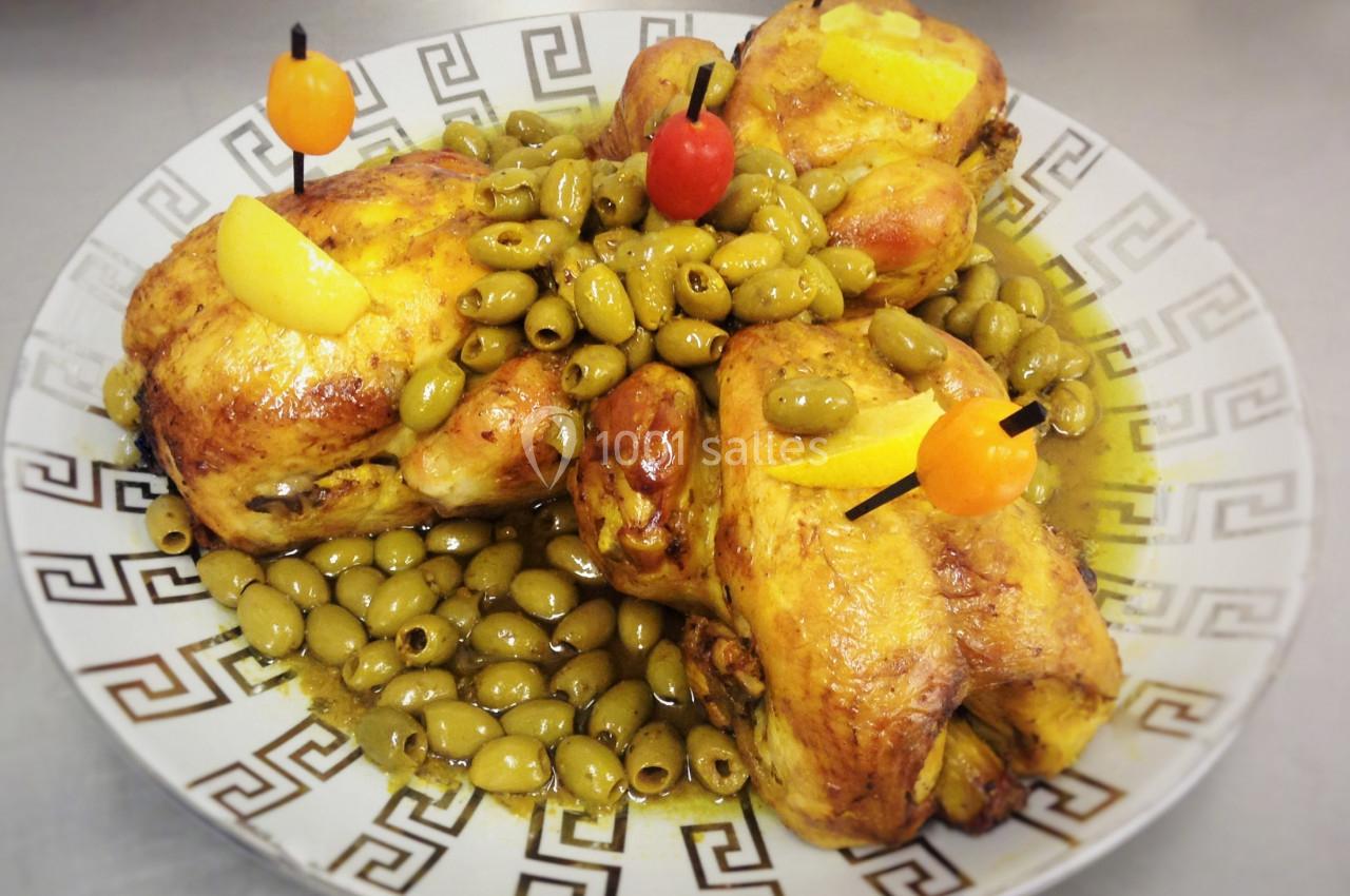 Poulets rôtis garnis d'olives vertes, décorés de tranches de citron et de brochettes colorées sur une assiette.