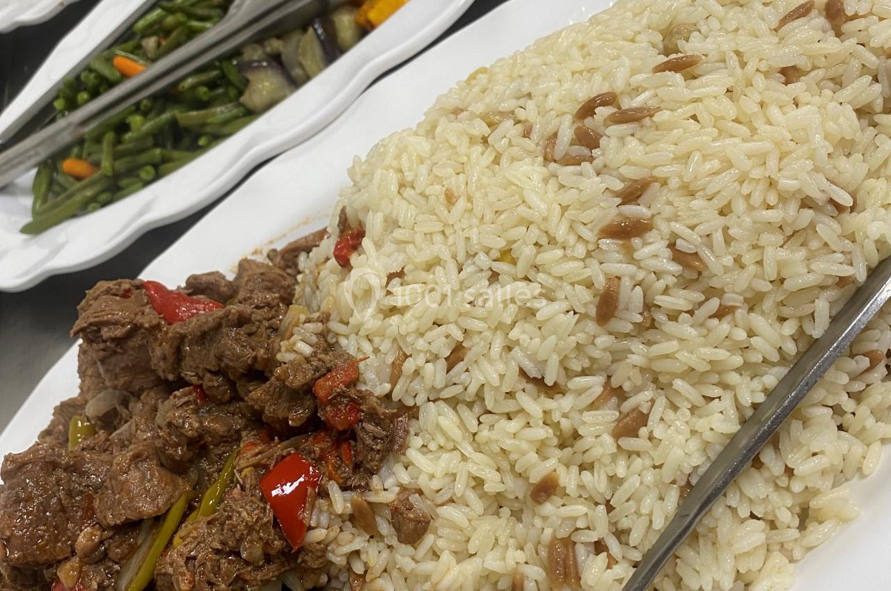 Assortiment de plats comprenant du riz, des légumes sautés, des morceaux de viande et des pommes de terre rôties.