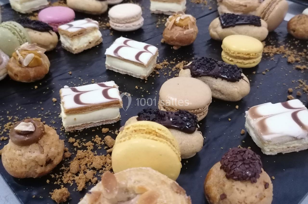 Plateau de pâtisseries variées comprenant macarons, éclairs, choux garnis et autres desserts disposés sur une table.