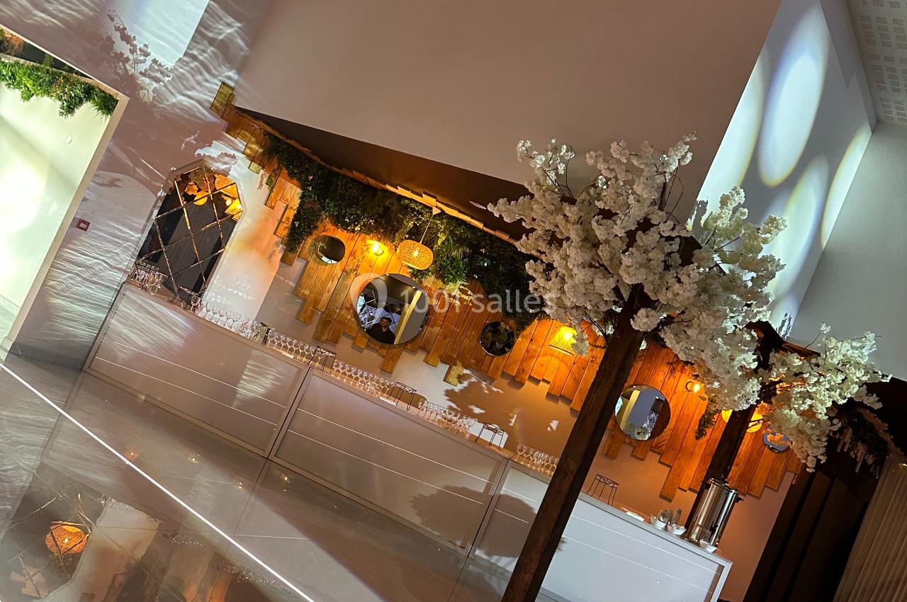 Décoration intérieure avec murs en bois, miroirs, éclairage chaleureux et arbre artificiel fleuri dans un espace moderne.