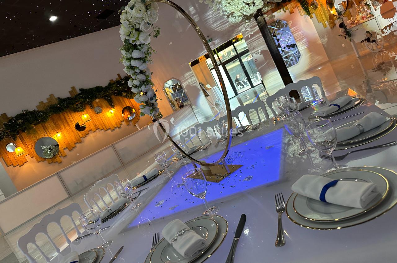 Table de réception élégamment dressée avec vaisselle raffinée, serviettes pliées et décoration florale suspendue.