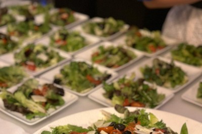 Buffet avec assiettes de salades variées, légumes frais et condiments, disposées sur une table éclairée.