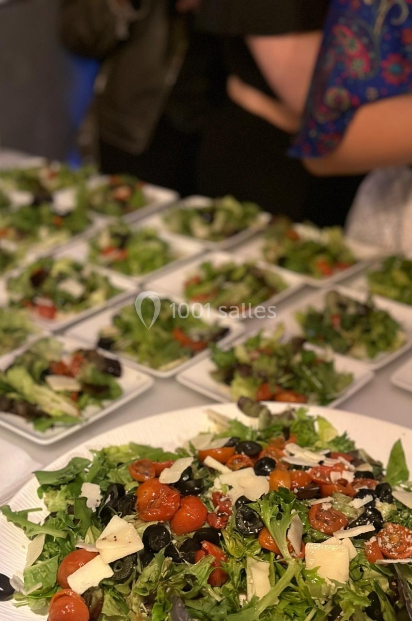 Assiettes de salade colorée avec tomates cerises, olives, fromage et feuilles vertes disposées sur une table.