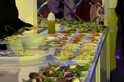 Buffet avec assiettes de salades variées, légumes frais et condiments, disposées sur une table éclairée.