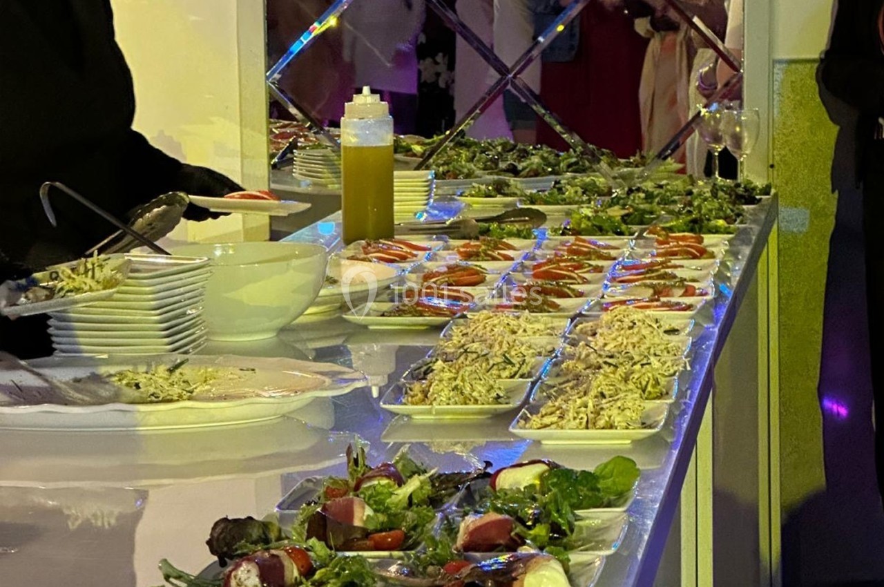 Buffet avec assiettes de salades variées, légumes frais et condiments, disposées sur une table éclairée.
