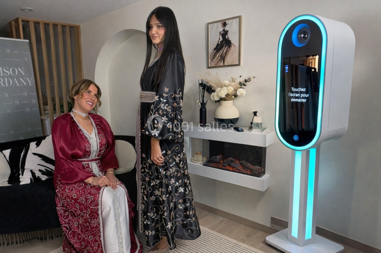 Deux femmes en robes traditionnelles posent près d'une borne photo interactive dans un intérieur élégant.