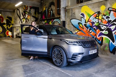 Chambre lumineuse avec lit double, table en bois, chaise beige, miroir et grande fenêtre avec stores.