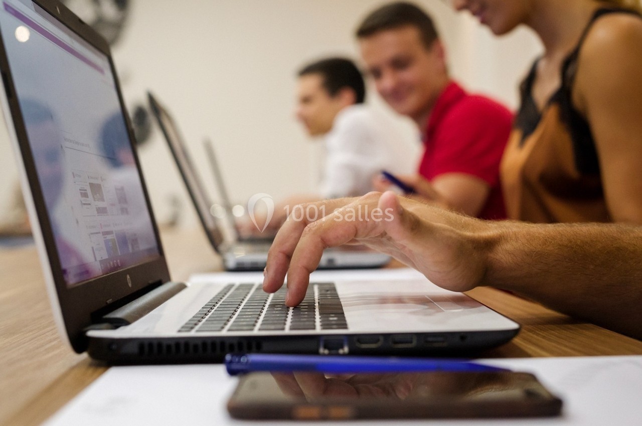 Personnes travaillant sur des ordinateurs portables dans un environnement de bureau collaboratif.