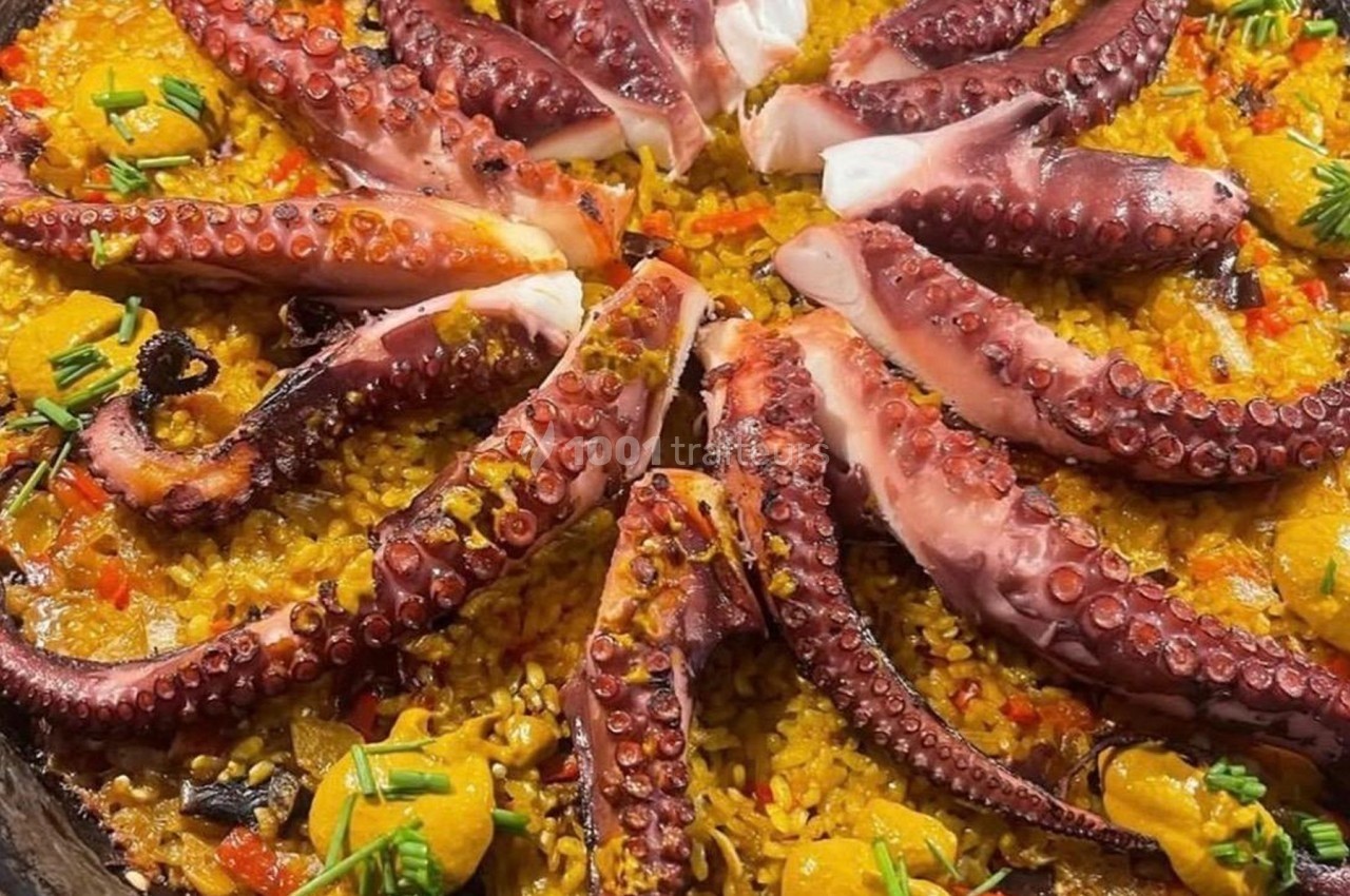 Plat de riz safrané garni de tentacules de poulpe grillées, légumes colorés et touches de sauce jaune.