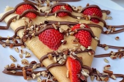 Des crêpes en cours de préparation sur des crêpières électriques, avec des personnes en arrière-plan.