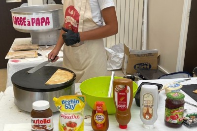 Des crêpes en cours de préparation sur des crêpières électriques, avec des personnes en arrière-plan.