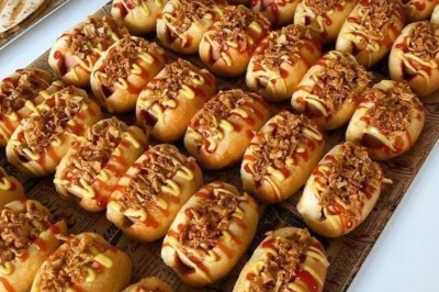 Des crêpes en cours de préparation sur des crêpières électriques, avec des personnes en arrière-plan.