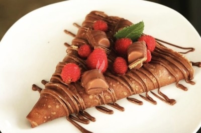 Des crêpes en cours de préparation sur des crêpières électriques, avec des personnes en arrière-plan.