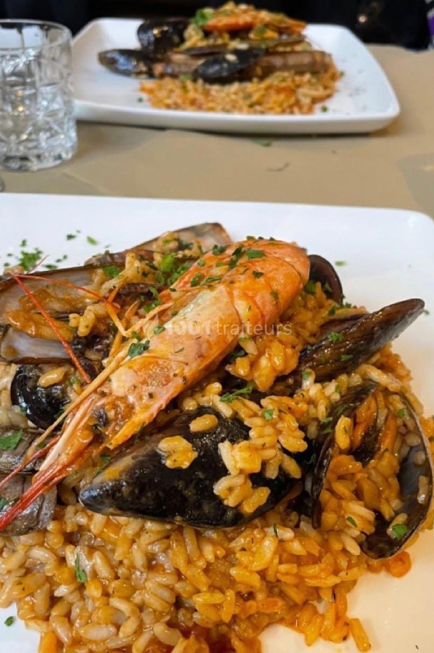 Assiette de riz cuisiné avec des fruits de mer variés, dont crevettes, moules et couteaux, garnie de persil.