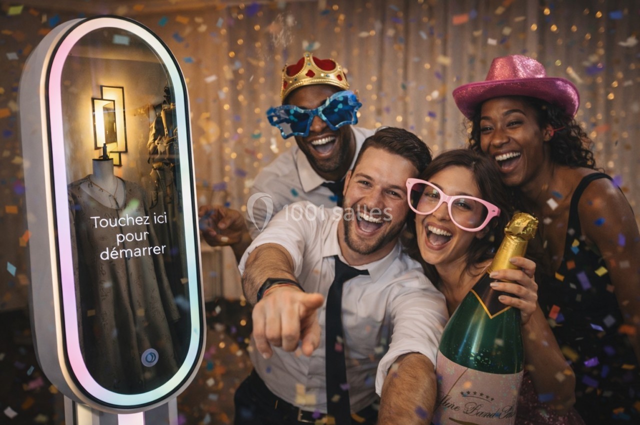 Des personnes souriantes posent devant une borne photo interactive, entourées de confettis et accessoires festifs.