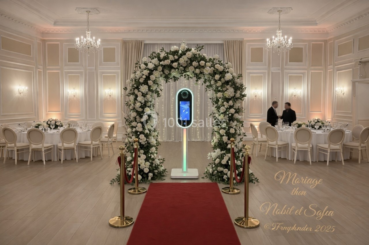 Arche florale ornée de roses blanches entourant une borne photo dans une salle de réception élégante.