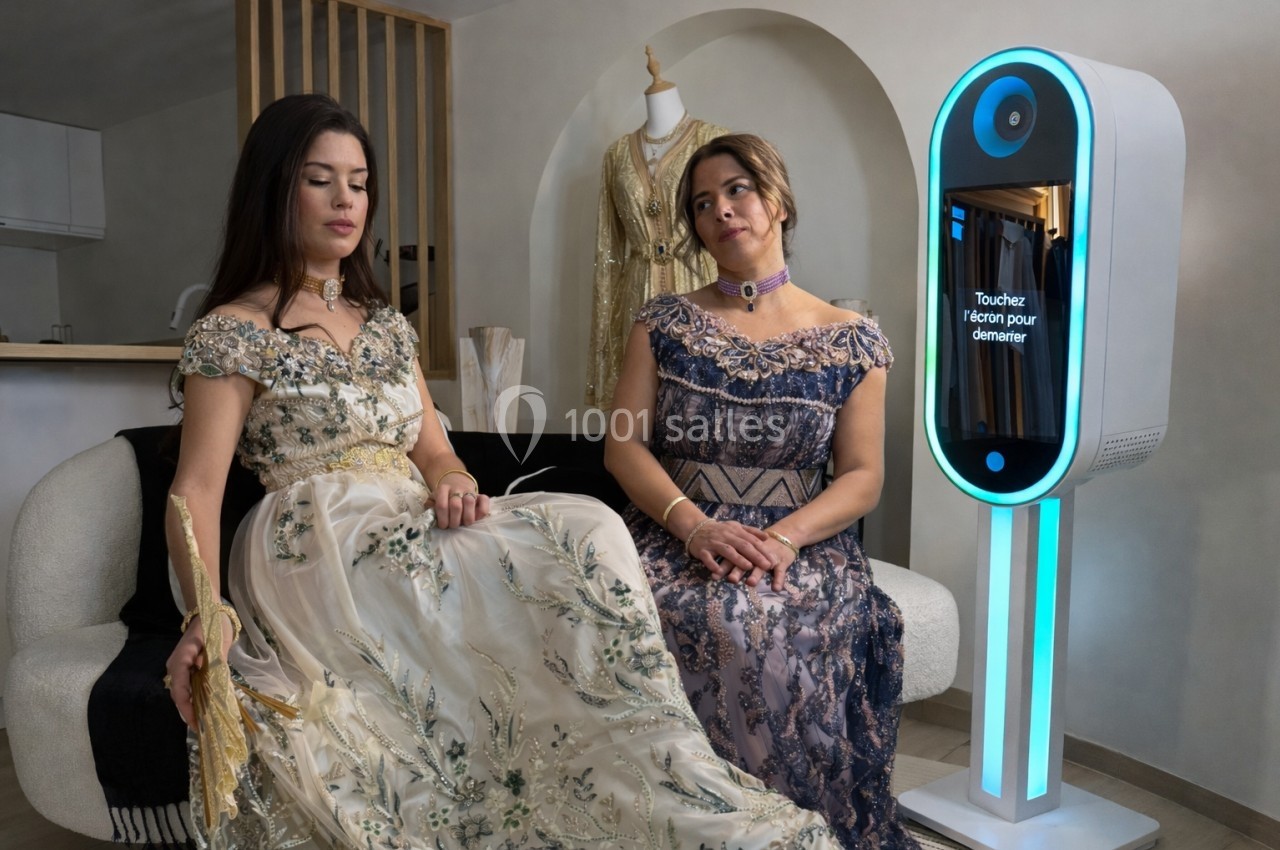 Deux femmes en robes élégantes assises près d'une borne interactive lumineuse dans un intérieur moderne.