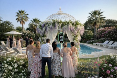 Deux personnes souriantes posant avec des accessoires festifs devant un fond scintillant rose.