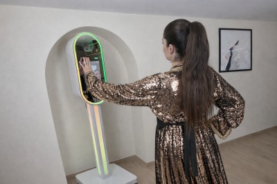 Deux personnes souriantes posant avec des accessoires festifs devant un fond scintillant rose.