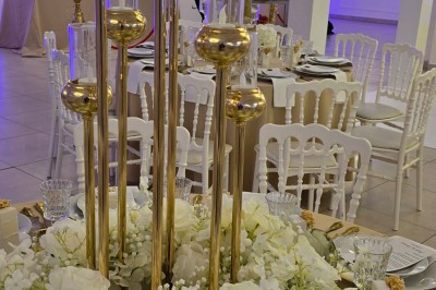 Miniature Location salle Mundolsheim (Bas-Rhin) - Le Joyau #11 Bougeoirs dorés élancés avec des fleurs blanches en décoration sur une table dans une salle de réception élégante.