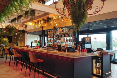 Cuisine professionnelle avec plans de travail en inox, étagères garnies d'ustensiles et équipements de nettoyage.