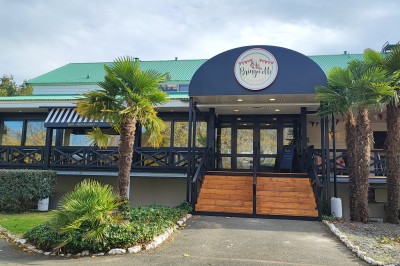 Cuisine professionnelle avec plans de travail en inox, étagères garnies d'ustensiles et équipements de nettoyage.