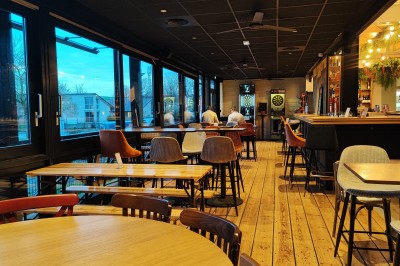 Cuisine professionnelle avec plans de travail en inox, étagères garnies d'ustensiles et équipements de nettoyage.