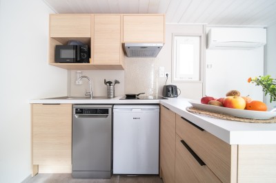 Miniature Location salle Ondres (Landes) - Camping Landae #6 Cuisine moderne avec meubles en bois clair, évier, lave-vaisselle, micro-ondes, réfrigérateur et corbeille de fruits.