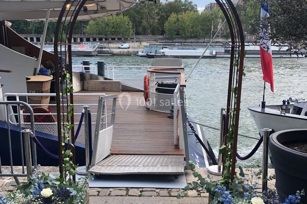 Arche décorée de fleurs bleues et blanches, installée près d'un ponton au bord d'une rivière.