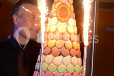 Terrasse d'un bateau avec des fauteuils, des plantes décoratives et une vue sur un pont et des arbres en arrière-plan.